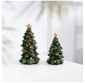 Detailed view of two miniature resin Christmas trees with colorful ornaments on a white pedestal.