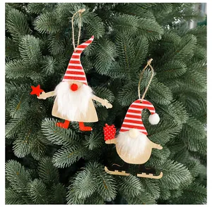 Detail view of two wooden Christmas gnome ornaments hanging on a green Xmas tree branch.