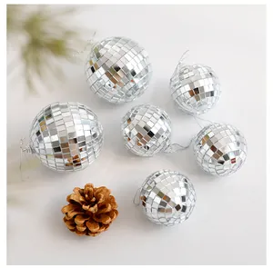 Detailansicht von silbernen Disco-Kugel-Weihnachtskugeln mit dekorativem Tannenzapfen