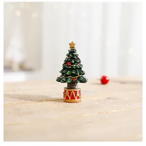 Close-up of a miniature resin Christmas tree with a gold star topper on a wooden table