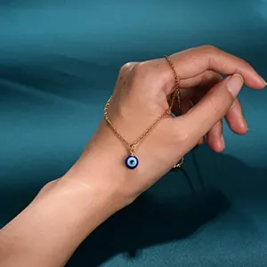Detail view of a gold chain necklace with a blue glass evil eye pendant on a hand.