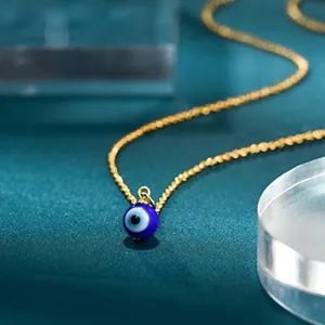Close-up view of a blue Evil Eye glass bead pendant on a delicate gold-tone chain