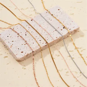 Close-up of multiple 18k gold plated necklace chain styles on a stone block