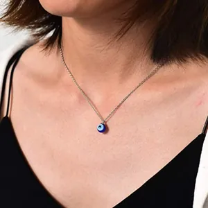 Close-up detail of a blue glass evil eye pendant necklace with a fine silver chain