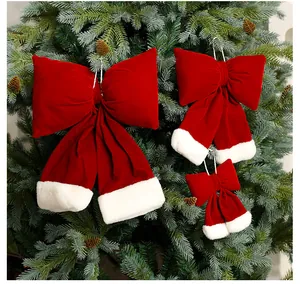 Detaillierte Ansicht roter Samt-Weihnachtsschleifen mit Pelzbesatz an einem Tannenbaum.