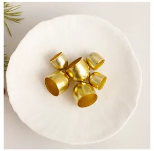 Macro detail of golden metallic Christmas tree hanging bells in a white bowl ornament