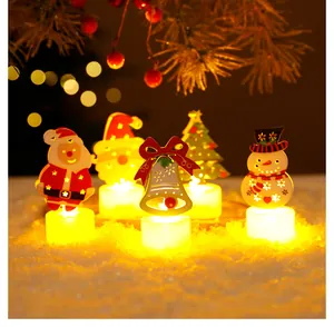 Gros plan de bougies chauffe-plat LED de Noël avec père Noël et bonhomme de neige sur la neige.