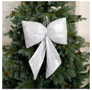 Detailansicht einer großen silbernen Metallschleife an einem grünen Weihnachtsbaum aufgehängt