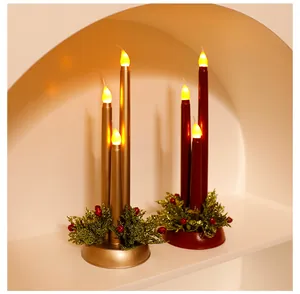 Elegante goldene und rote LED-Weihnachtskerzen mit festlichen Tannenzweigen und Beeren