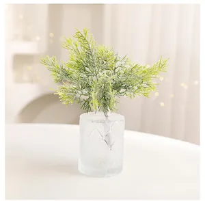 Detailed view of artificial green cypress with snowy frosted effect in a diamond glass vase.