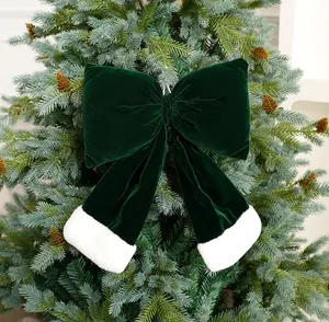 Große dunkelgrüne Weihnachtsschleife aus Samt mit weißem Pelzbesatz am Baum