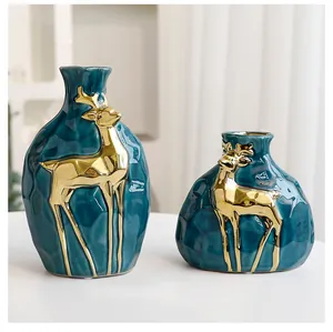Detailaufnahme von zwei blauen Keramikvasen mit goldenen Hirschmotiven für die Weihnachtsdeko.