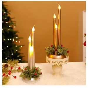 Elegante goldene und silberne LED-Stabkerzen mit weihnachtlichem Grün auf weißem Grund