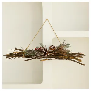 Rustic Christmas twig door hanging decorated with pine cones and berries on a white shelf.