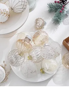 Gros plan de boules de Noël pailletées blanc et or sur une assiette blanche