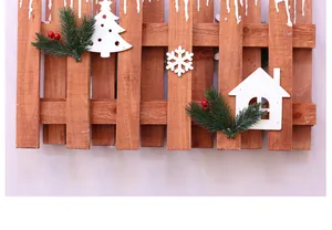 Detail eines rustikalen Weihnachtsholzzauns mit weißen Baum- und Hausdekoren
