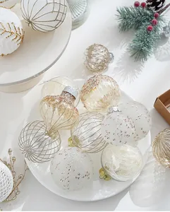 Close-up of elegant white and gold Christmas ornaments with glitter and wire patterns.