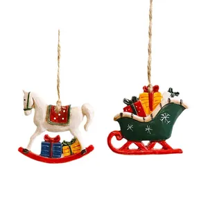 Pair of Christmas resin ornaments featuring a white rocking horse and green sleigh