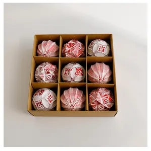 Detailweergave van 9 rood-wit gedessineerde kerstballen in een geschenkverpakking