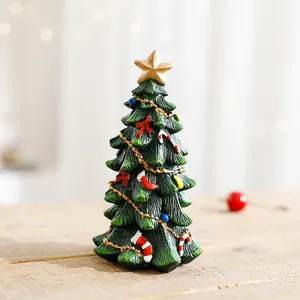 Miniature resin Christmas tree figurine with gold star and festive ornaments on wooden table