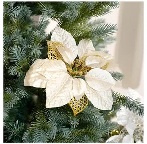 Gros plan d'un élégant poinsettia artificiel blanc et or sur les branches d'un sapin de Noël