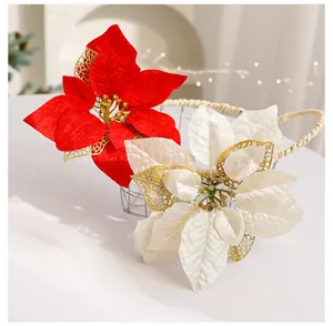 Vue détaillée de fleurs de poinsettia artificielles en tissu rouge et champagne festif.