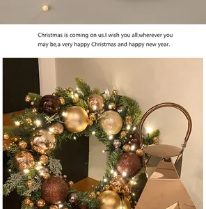 Vista detallada de una corona de Navidad con bolas doradas y luces LED cálidas
