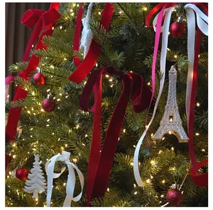 Eleganti nastri di velluto rosso e raso bianco su un albero di Natale decorato con luci.