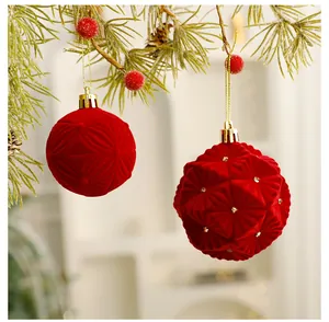 Close-up of red flocked Christmas ball ornaments with velvet texture hanging on pine.