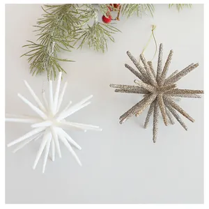 Detailed view of white and champagne starburst Christmas ornaments on pine branch