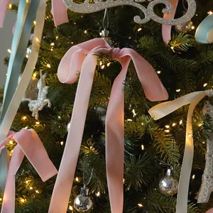 Eleganti fiocchi in velluto rosa che decorano un albero di Natale luminoso per le feste.