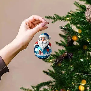 Hand holding a 2D acrylic Santa Claus hanging ornament decoration near a Christmas tree