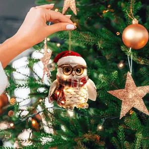 Hand holding a cute owl Christmas tree ornament with festive lights and Santa hat