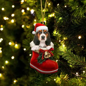 Χριστουγεννιάτικο στολίδι σκύλος Basset Hound σε κόκκινη κάλτσα σε φωτισμένο εορταστικό δέντρο