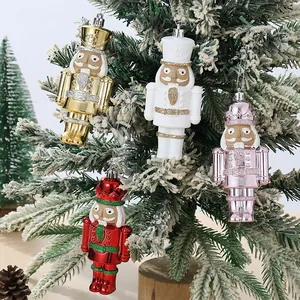 Juego de cuatro coloridos adornos de cascanueces de plástico colgando en un árbol de Navidad nevado