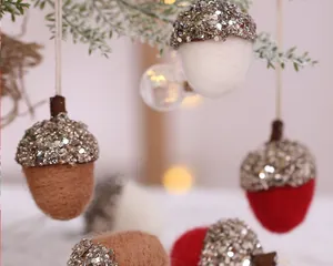 Décorations de Noël en forme de glands en feutre pailleté suspendues à une branche