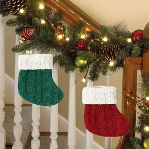 Mini red and green knitted Christmas stockings hanging on staircase garland.