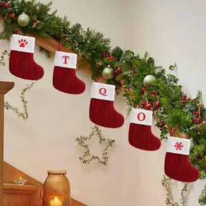 Set of red knitted Christmas stockings with letters hanging on a festive green garland