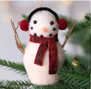 Dettaglio di un pupazzo di neve in peluche con paraorecchie rossi per l'albero.