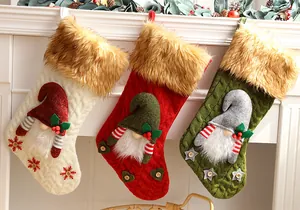 Close-up view of three knitted Christmas stockings with plush gnome designs on a white mantel.