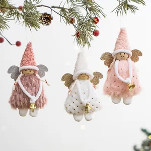 Cute plush Christmas angel ornaments with bells hanging on a pine tree branch