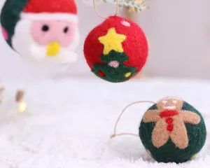 Ornements de Noël en boules de feutre faits main avec motifs Père Noël et bonhomme de pain d'épices.