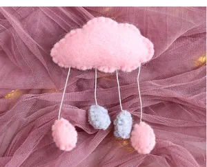 Gros plan d'un ornement de nuage en feutre rose avec des gouttes de pluie déco