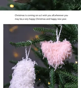 Close-up view of pink and white fuzzy heart ornaments hanging on a green Christmas tree
