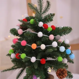 Guirlande de pompons de Noël multicolore accrochée à un sapin de fête décoré