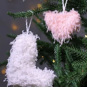 Fuzzy pink heart and white sock feather ornaments hanging on a green Christmas tree branches