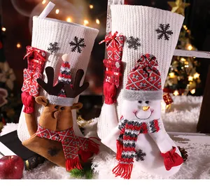 Detailopname van witte gebreide kerstsokken met 3D-figuren van rendieren en sneeuwpoppen.
