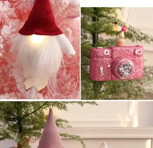 Nahaufnahme von funkelnder rosa Kamera und leuchtendem Zwerg-Weihnachtsschmuck
