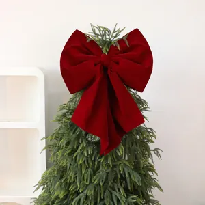 Large burgundy velvet bow topper for Christmas tree decoration and festive atmosphere.