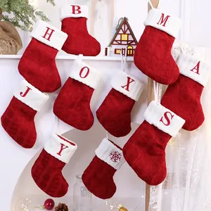 Detailansicht von roten gestrickten Weihnachtsstrümpfen mit gestickten Buchstaben und Flocken
